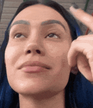 a close up of a woman 's face with a finger pointing to her forehead