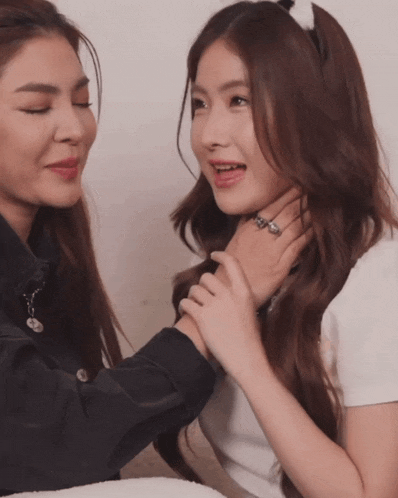 a woman is holding another woman 's neck and they are looking at each other