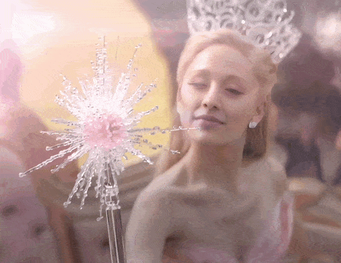 a woman in a tiara holds a fairy wand