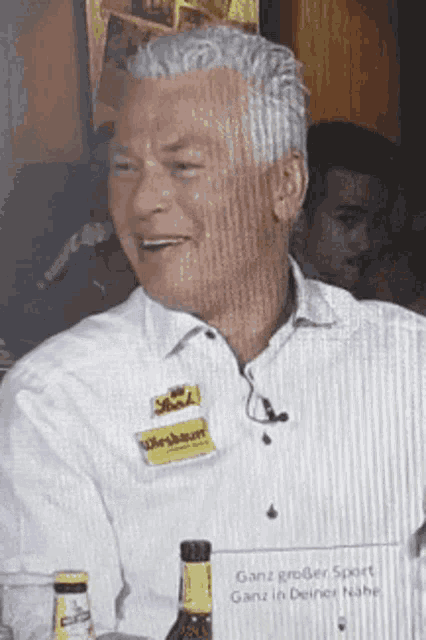 a man in a white shirt has a name tag that says " ganz großer sport "