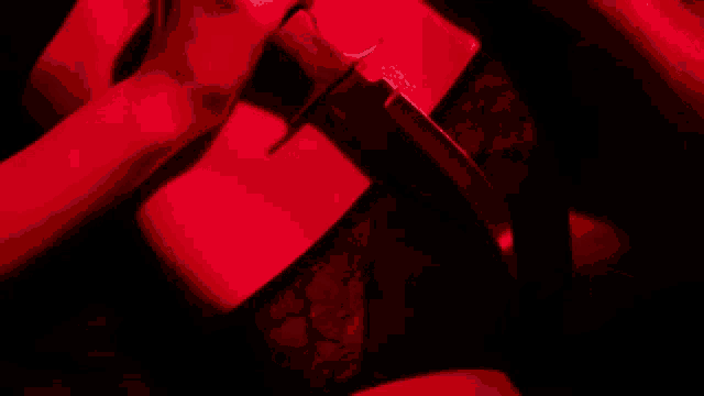 a woman in a red light is holding a knife .