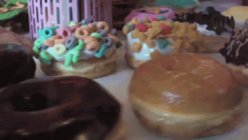 a variety of donuts are on a table including one with cereal on top