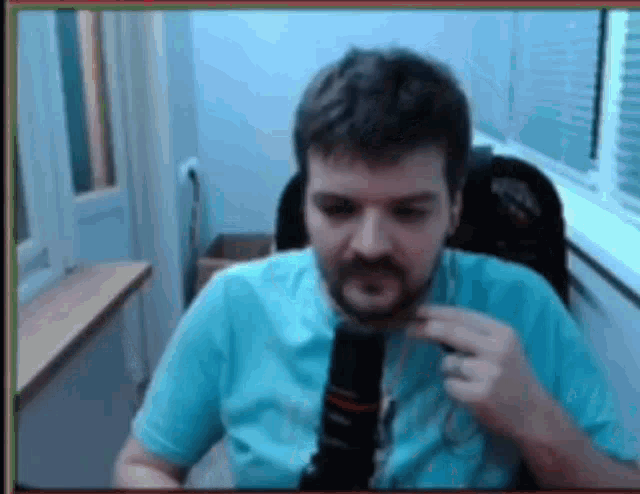 a man with a beard is sitting in a chair with a microphone in front of him .