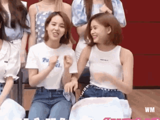 a group of young women are sitting next to each other in a room and laughing .