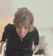 a man in a black shirt is making a funny face while sitting at a table .