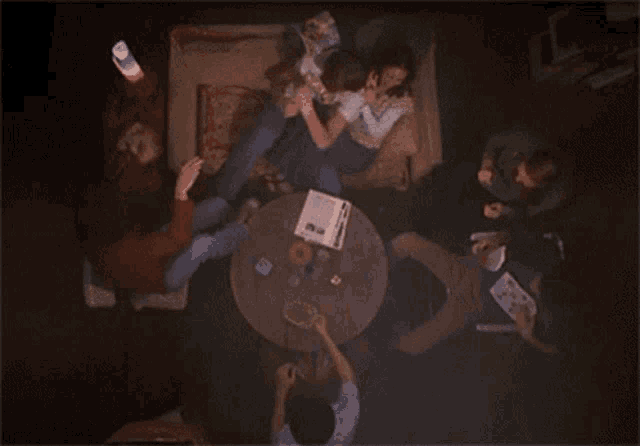 a group of people are sitting around a table playing cards