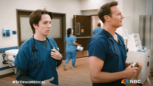 two doctors are standing in a hospital hallway with a nbc logo on the bottom