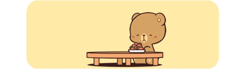a teddy bear is sitting at a table eating strawberries