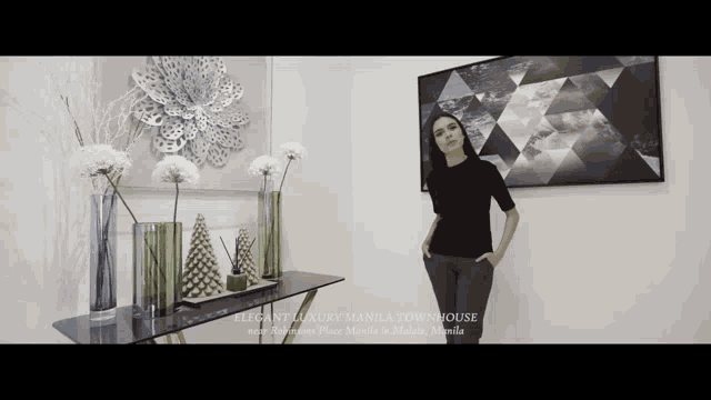 a woman stands in a room with a sign that says elegant luxury manila townhouse next to her