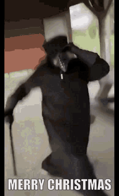 a man in a black robe and top hat is holding a cane and saying merry christmas