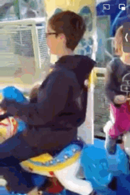 a boy and a girl are riding a merry go round in an arcade