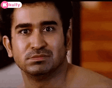 a man without a shirt is making a funny face and looking at the camera .