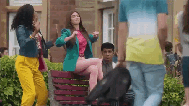 a woman in a green jacket sits on a bench with other people