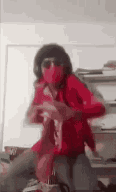 a person in a red shirt and sunglasses is sitting on a couch .
