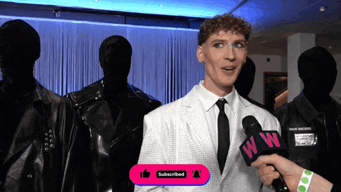 a man in a suit and tie is being interviewed by someone with a microphone that says ww