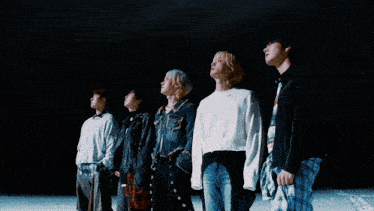a man with blonde hair and a white sweater looks up at the sky