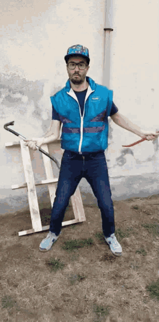 a man in a blue vest is holding a hammer and a ladder