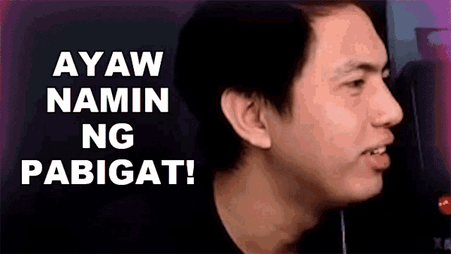 a man is sitting in front of a computer screen with the words ay aw namin ng pabigat written on the screen .