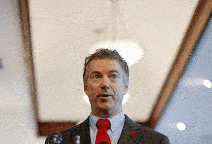 a man in a suit and tie stands in front of a microphone