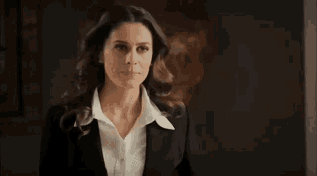 a woman in a suit and white shirt is smiling .