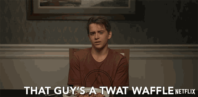 a man sitting at a table with a plate of food and the words that guy 's a twat waffle netflix