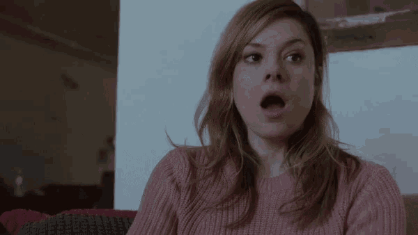 a woman in a pink sweater has her mouth open in surprise