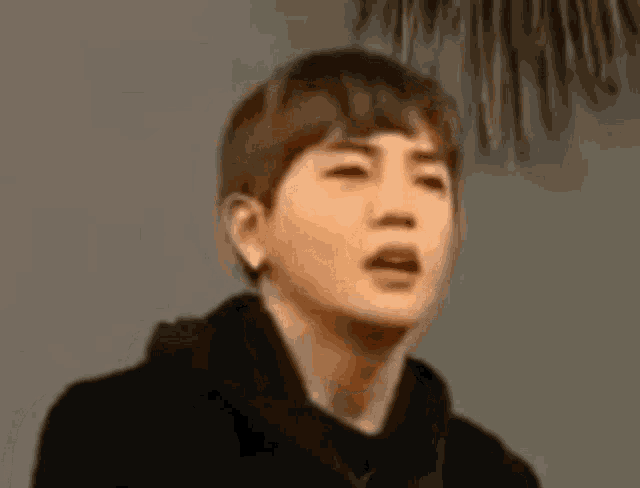 a young man in a black hoodie is making a funny face with his mouth open .