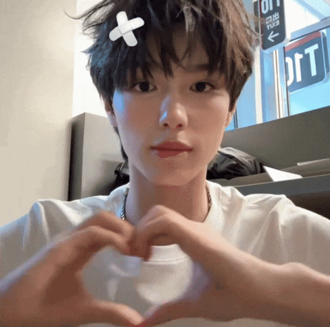 a person with a bandage on their head making a heart shape with their hands