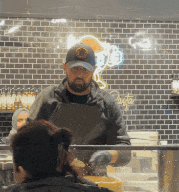 a man prepares food in front of a pasta sign