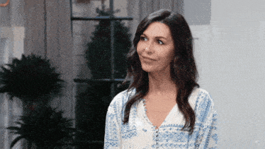 a woman in a blue and white shirt is smiling in a room