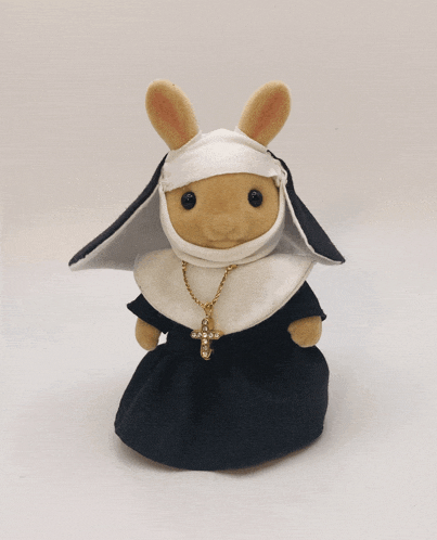 a stuffed bunny is dressed as a nun and has a cross necklace around her neck