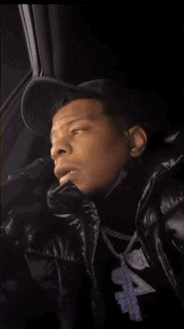 a man wearing a hat and a black jacket is sitting in a car .