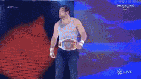 a man wearing a wrestling belt is walking down a ramp .