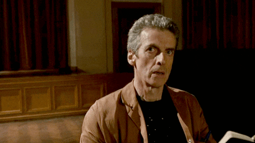 a man in a brown jacket and black shirt is reading a book