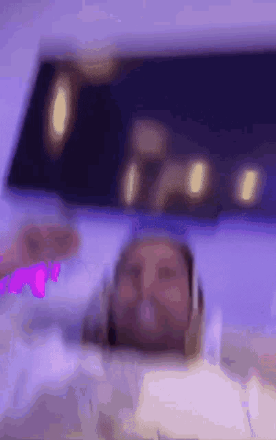 a blurry picture of a person wearing headphones laying in a bed .