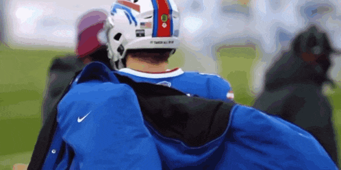 a man wearing a buffalo bills helmet carrying a blue jacket