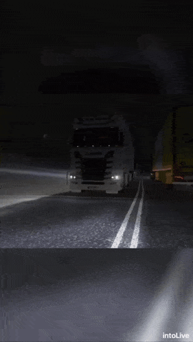 a scania truck is driving down a dark highway