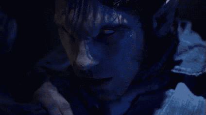 a close up of a werewolf with red eyes looking at the camera in the dark .
