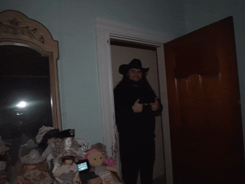 a man in a cowboy hat is standing in a dark room