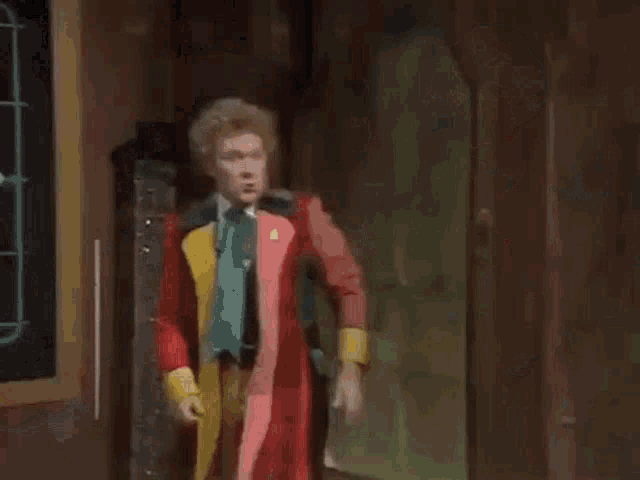 a man in a red coat is dancing in a room .
