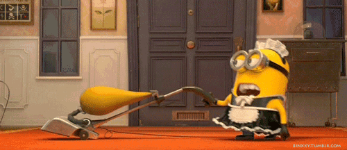 a minion in a maid costume is using a vacuum cleaner in a room