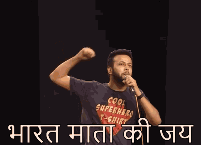 a man in a cool superhero t-shirt sings into a microphone