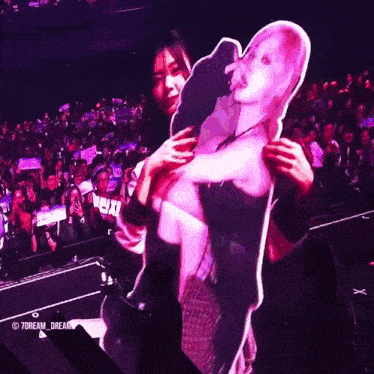 a woman is holding a cardboard cutout of a woman in front of a crowd