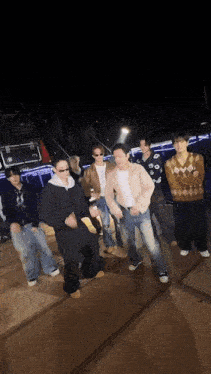 a group of young men are standing on a stage dancing