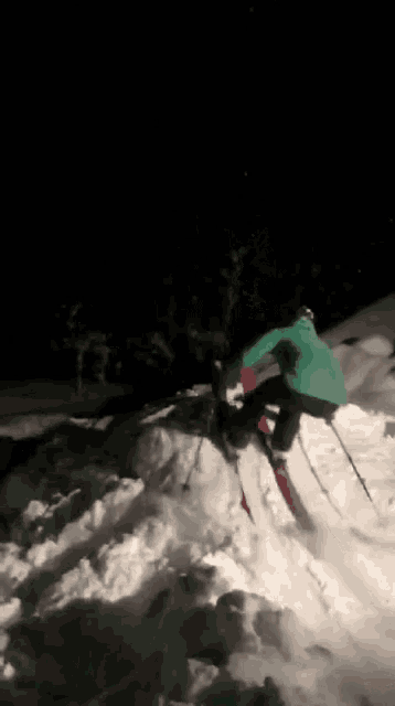 a person is skiing down a snow covered hill at night