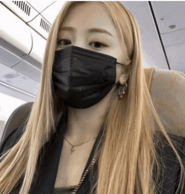 a woman with long blonde hair wearing a black mask