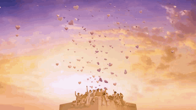 a group of people sitting on top of a building with hearts flying in the sky