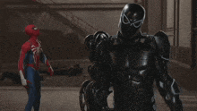 a man in a spiderman suit is standing next to another man in a black suit