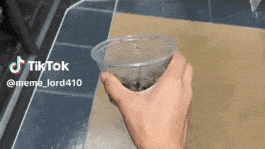 a person is holding a plastic cup with a tiktok watermark on the bottom