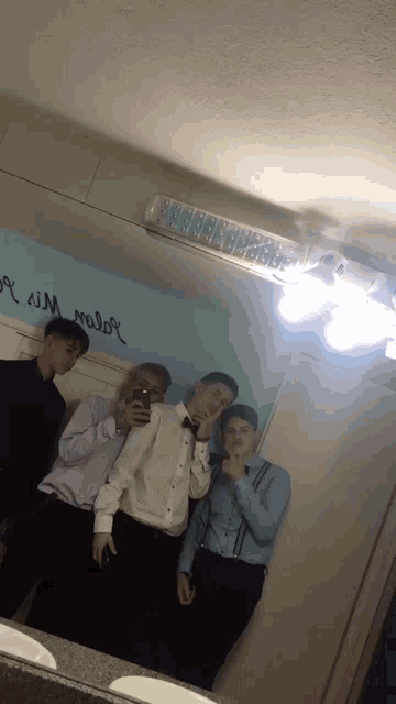 a group of young men are taking a picture of themselves in front of a mirror that says " i love you " on it